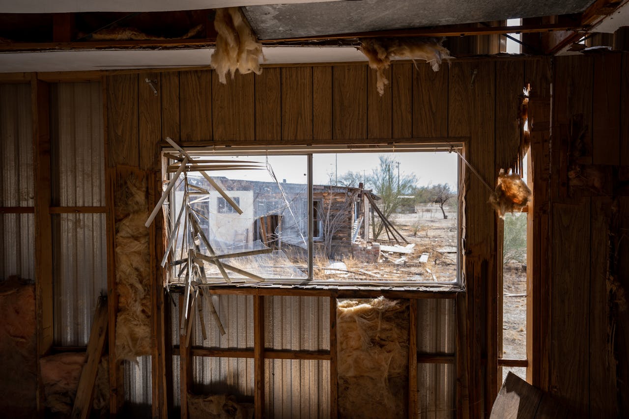Explore an eerie view through a broken window of an abandoned structure in Arizona's desert landscape.