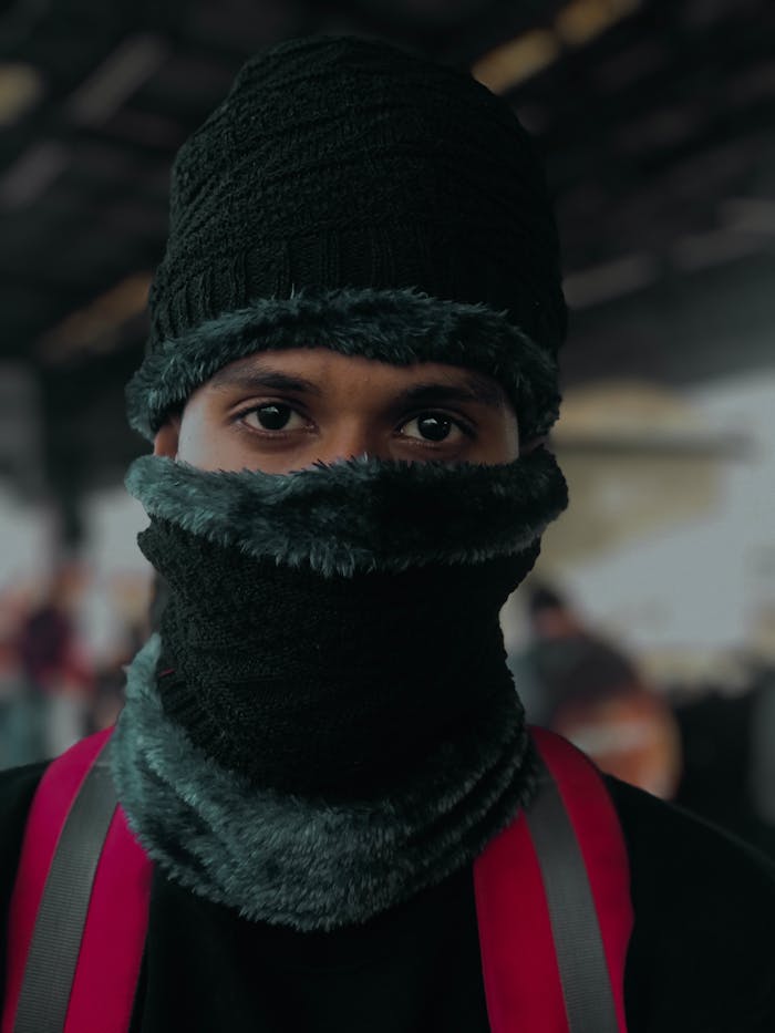 Man wearing a black balaclava, staying warm against the cold with focused gaze.